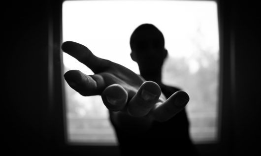 Imagen de una silueta oscura estirando la mano y brindando ayuda.
