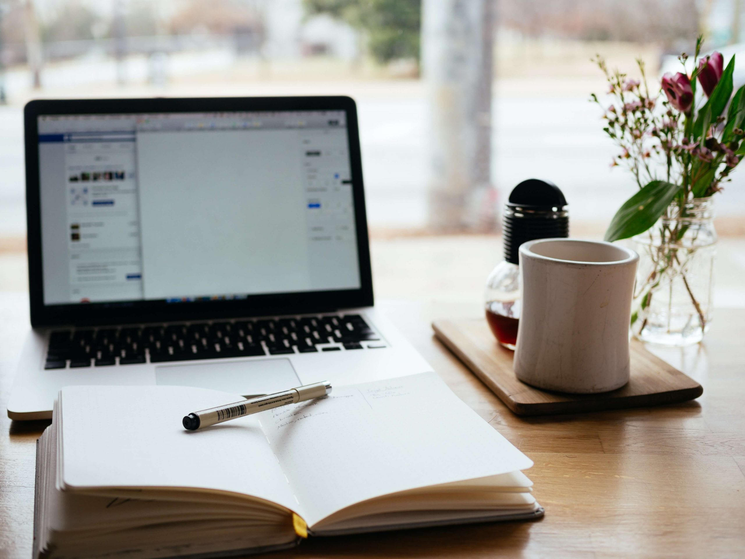 Imagen de notebook junto con un libro, una taza y un lapicero representando el aprendizaje online.