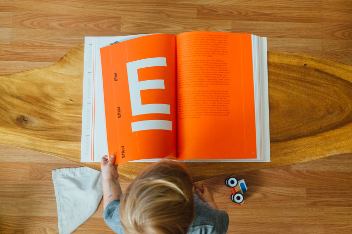 Ilustración de un niño leyendo un libro con la letra E en el centro representando los cursos en línea.
