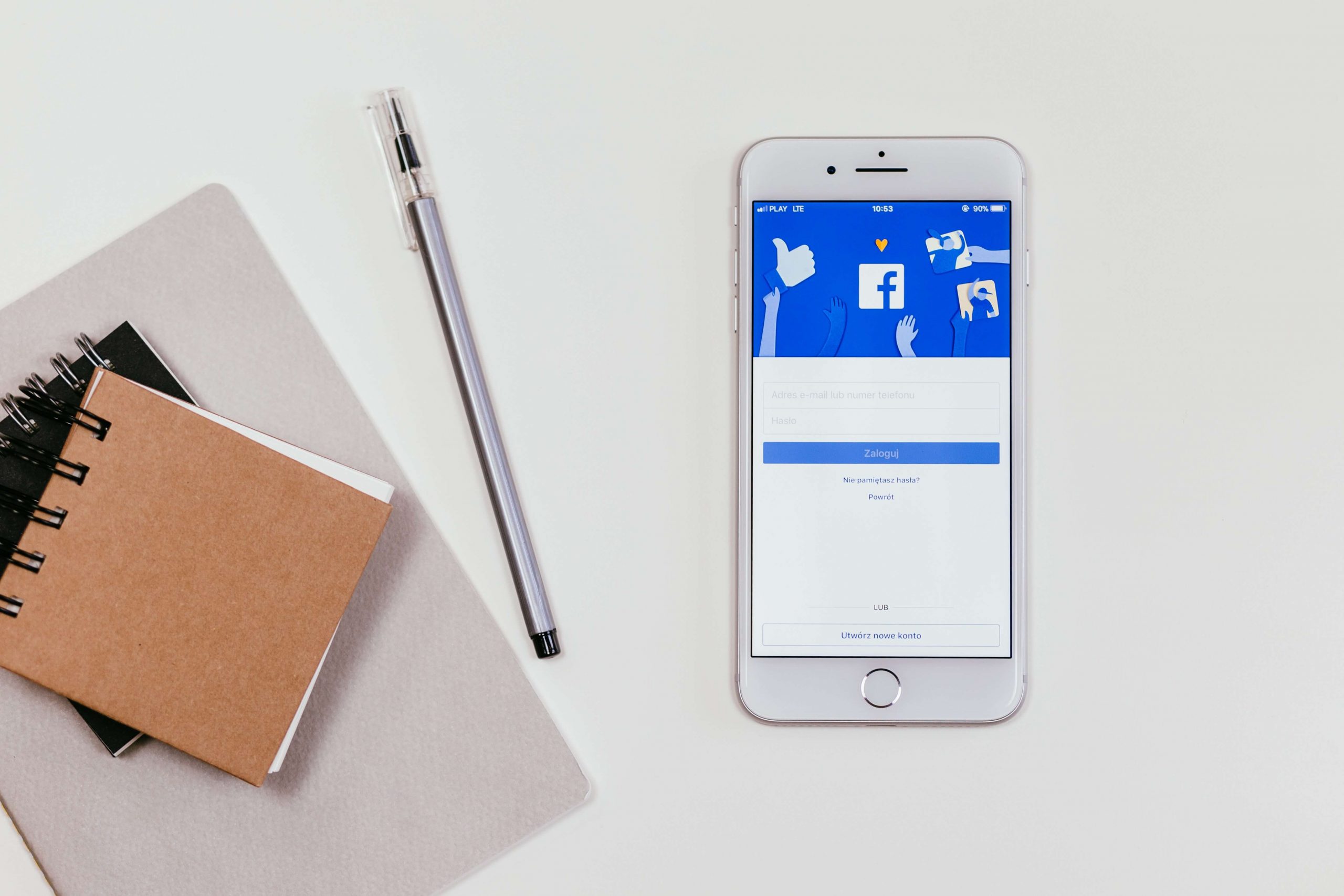 Imagen que muestra una agenda, un lapicero y un teléfono con una de las redes sociales más usadas abierta: Facebook