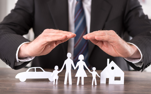 Imagen de una persona protegiendo con sus manos algunas figuras como una familia, una casa y un carro, haciendo clara referencia a los seguros.