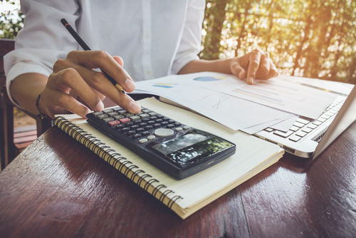 Imagen de una persona calculando sus gastos personales en una calculadora sobre un cuadernillo.