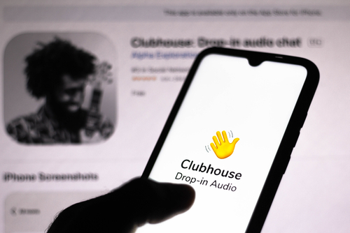 Imagen de un celular con la mano representativa de ClubHouse dando la bienvenida a la aplicación.