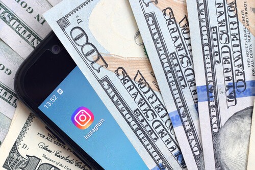 Imagen que muestra un celular con la aplicación de Instagram y al costado algunos dólares haciendo referencia a monetizar en Instagram.