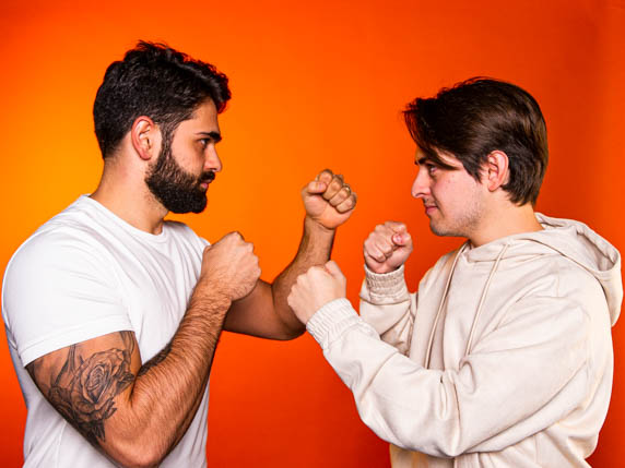 Tráfego pago ou orgânico? Foto do Pedro Sobral em posição inicial de luta, de frente para Hyeser que também está em pose de luta. Os dois vestem roupas claras, estão de frente um para o outro em um local de fundo laranja.