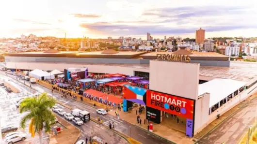 Vista aérea do centro de eventos Expominas, em Belo Horizonte, durante o Hotmart Fire, com entrada personalizada, estruturas coloridas, público circulando e área externa preparada para o evento.
