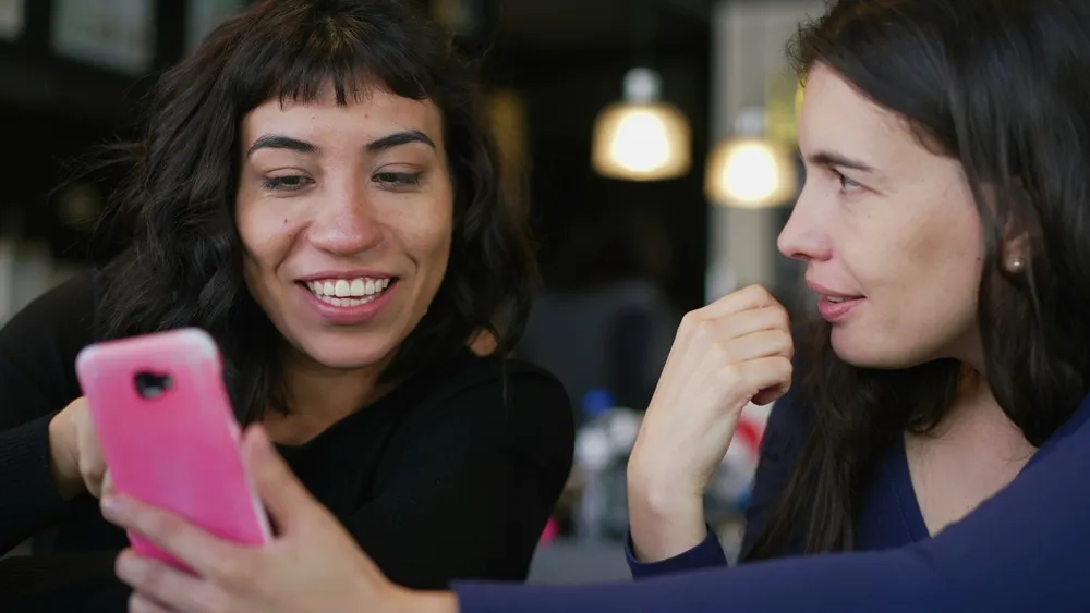 Two women looking at a phone, best times to post on TikTok