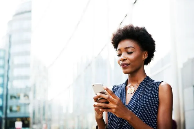 Mujer en un entorno urbano usando el celular para enviar mensajes por WhatsApp
