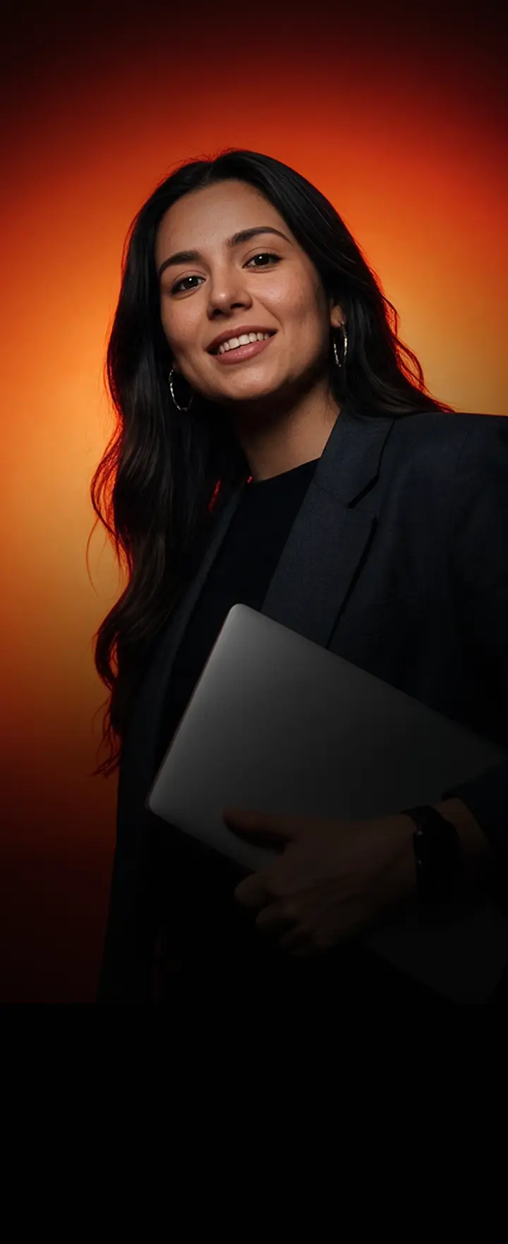 Retrato de una emprendedora con laptop en mano, iluminada por un fondo naranja, símbolo de quienes construyen su negocio digital con Hotmart LATAM.