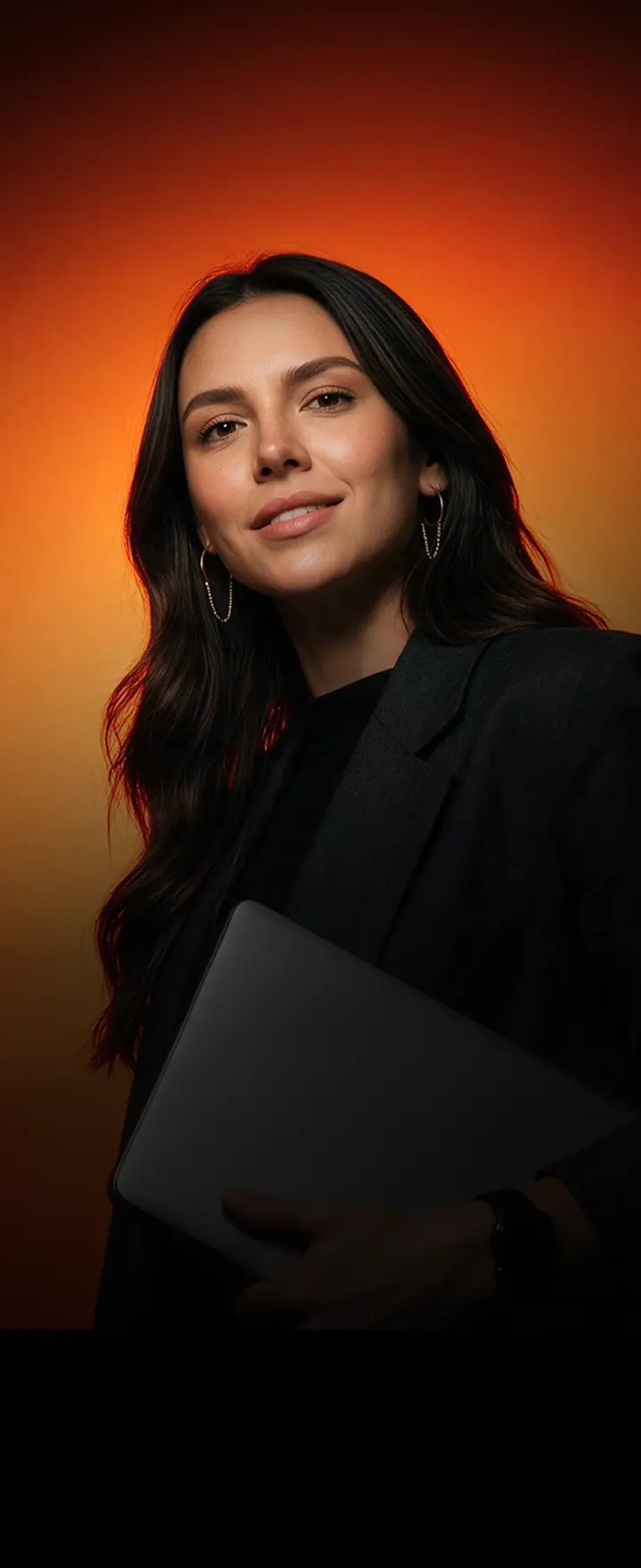 Mujer creadora sostiene una laptop frente a un fondo naranja, representando a profesionales que usan Hotmart para construir y hacer crecer su negocio digital.
